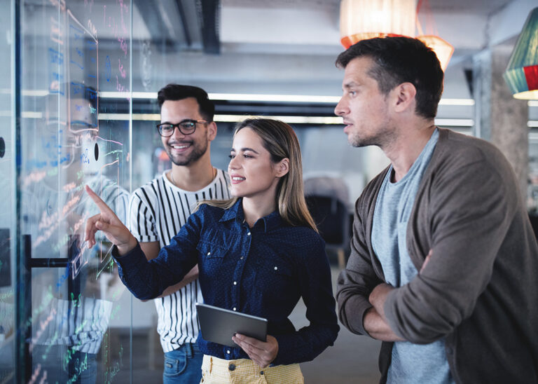 Bild zeigt Mitarbeiter, die ein Whiteboard aus Glas betrachten.
